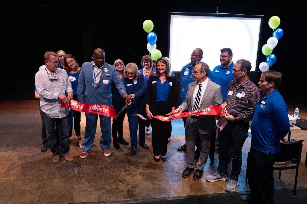 The Collaborative Labs team cuts a large ribbon with gold scissors to mark the opening of their second location.
