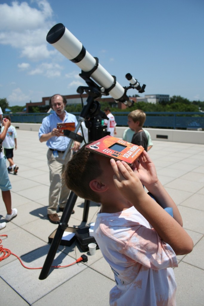 A small child views a previous eclipse through an eclipse viewer on the roof of the SPC Planetarium.